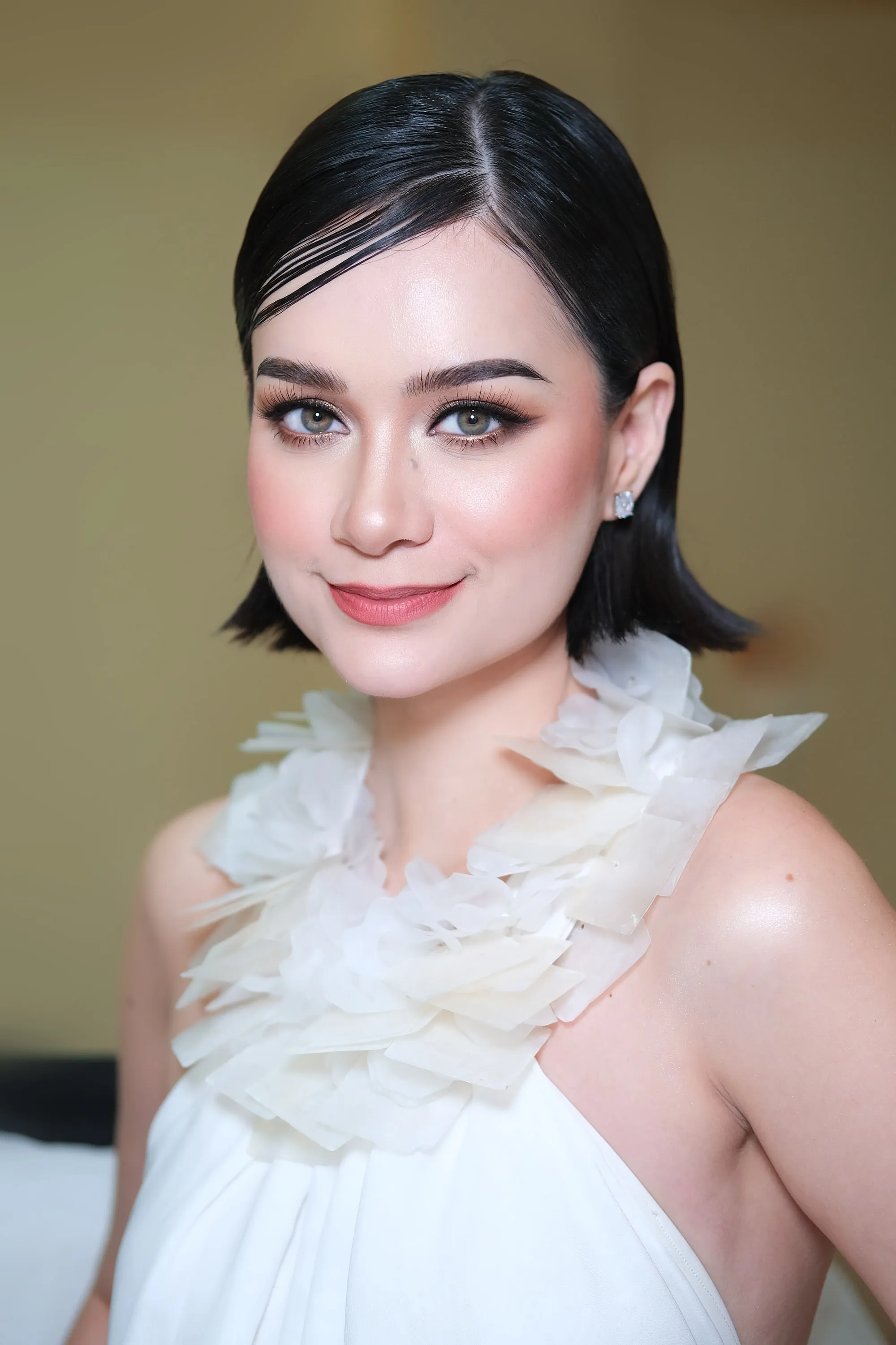 The same bob and ruffled collar seen closer, with the shimmer on the lid and the sculpted cheek visible.