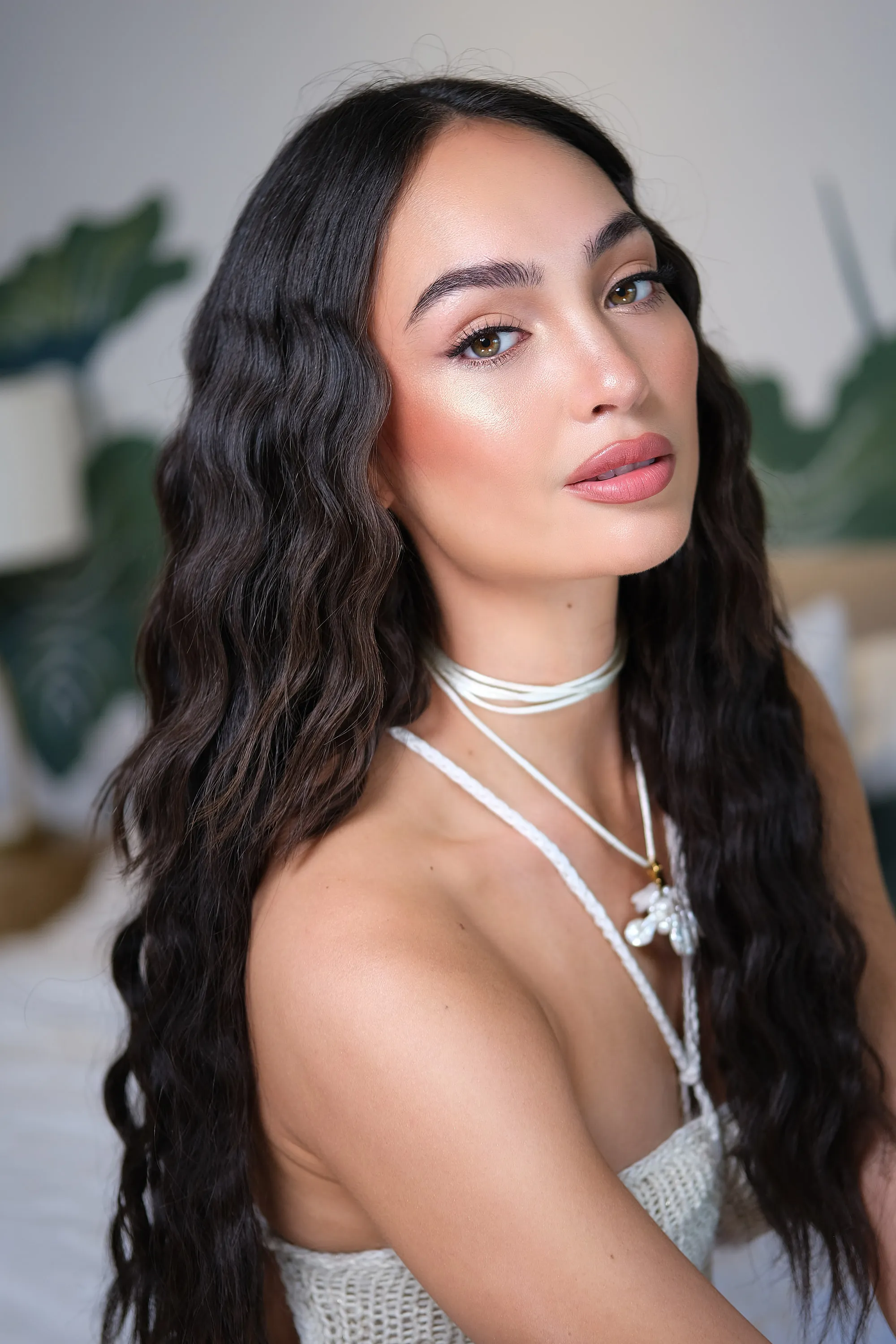 The same high-shine editorial look at three-quarter angle, with the highlight along the cheekbone and collarbone.