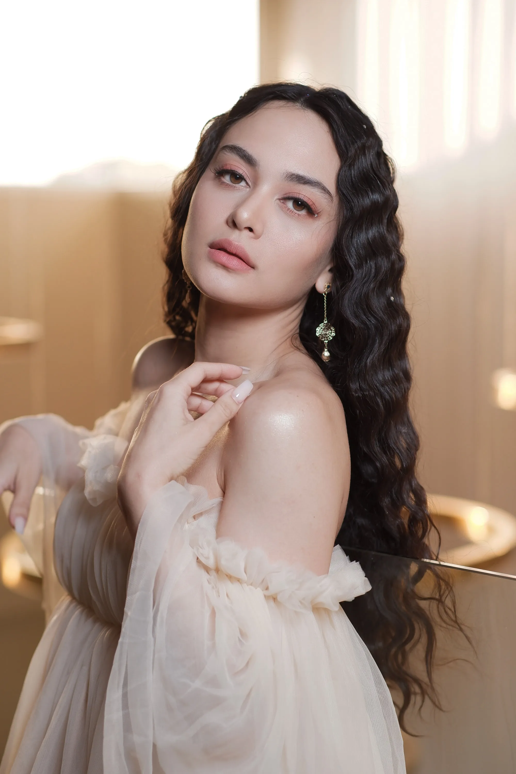 Editorial make-up with a soft warm eye and a bare lip, photographed in candlelight with long curls and sheer tulle.
