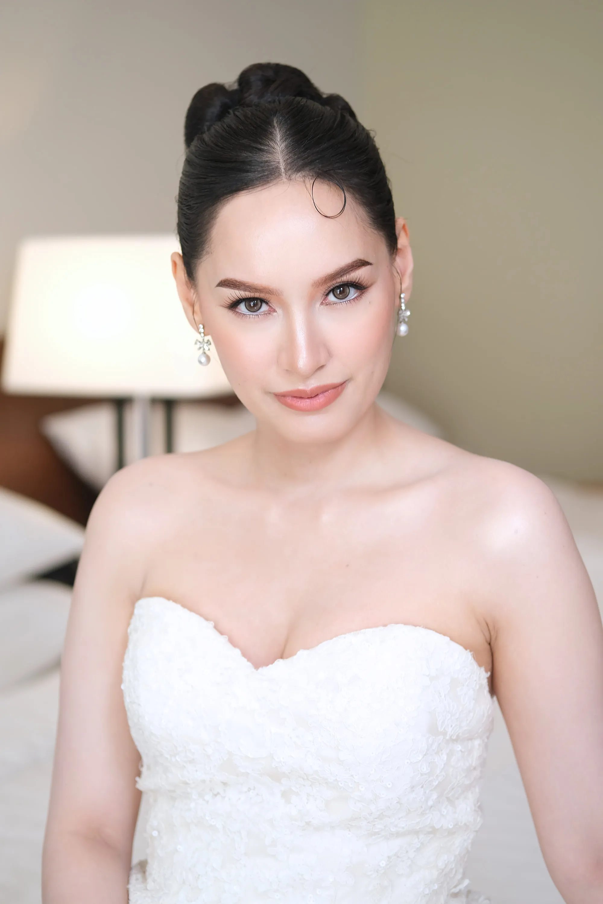 Bridal make-up with a clean matte base and a nude rose lip, worn with a low updo and a sweetheart lace gown.