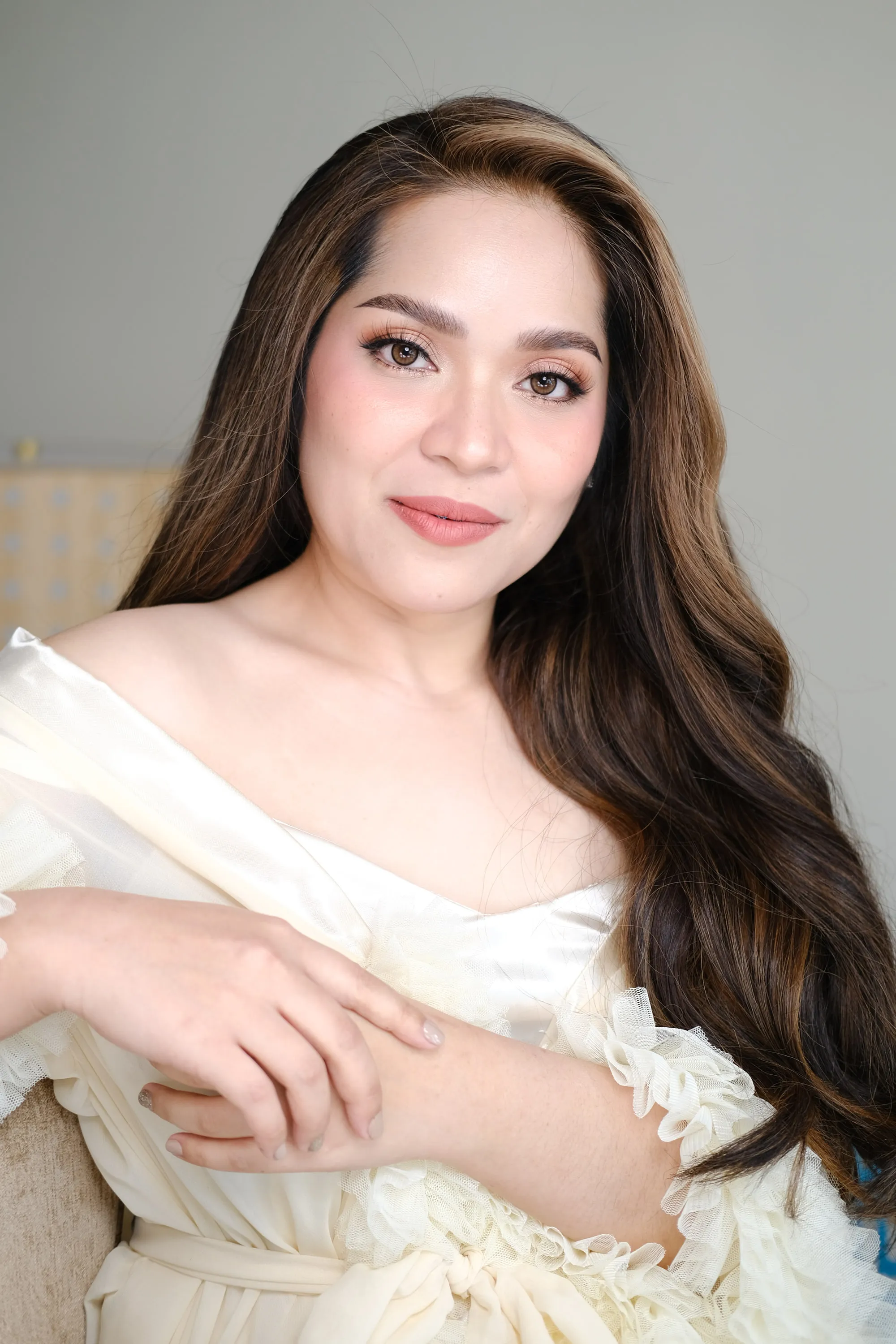 Bridal make-up with warm shadow and a soft nude lip, worn with honey-toned waves and a champagne ruffled gown.