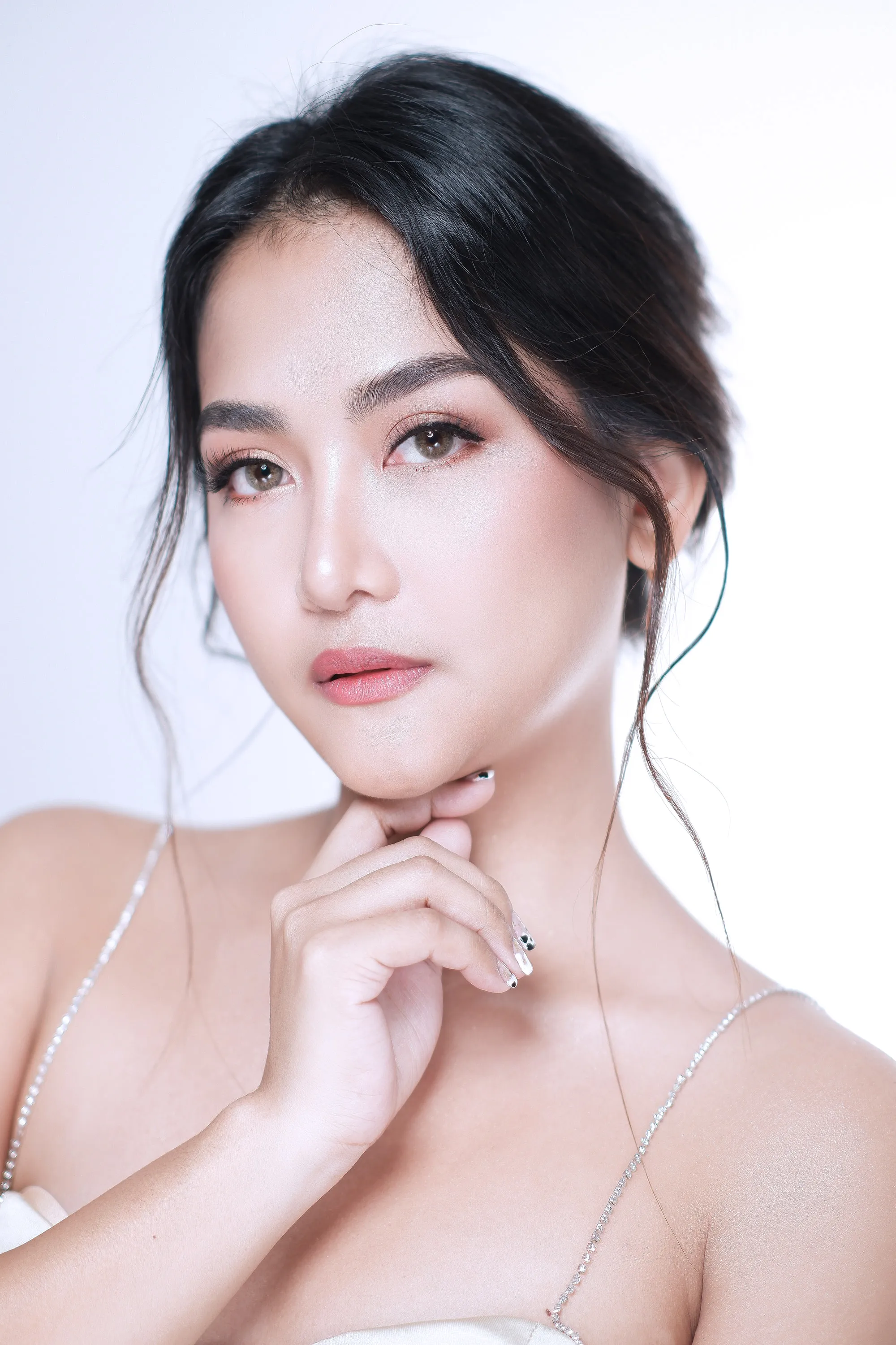Studio bridal make-up with a nude lip and a soft smoked lash line, worn with an updo and loose face-framing tendrils.